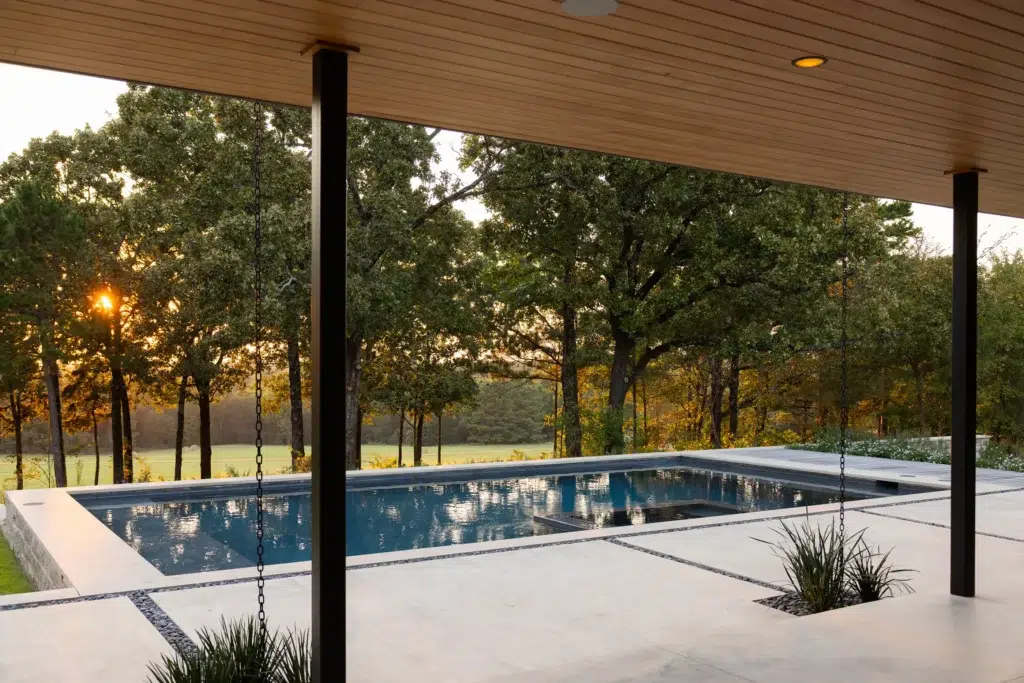 Covered patio and custom pool with wooded view for the Pine Mills outdoor living project