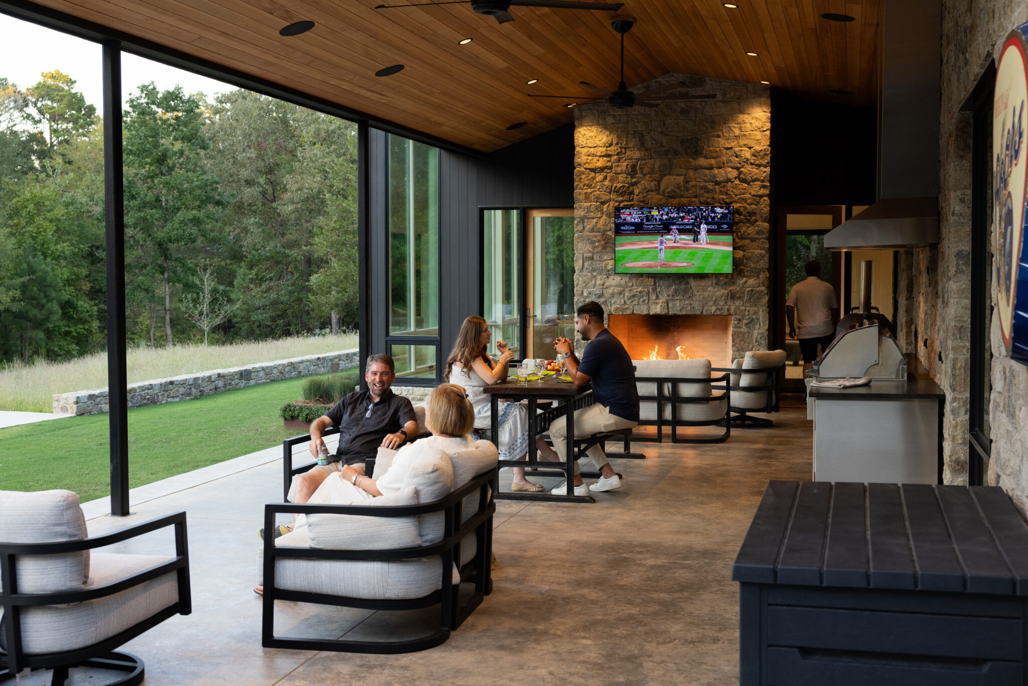 Custom covered porch with outdoor fireplace, lounge seating, and built-in entertainment area in East Texas.